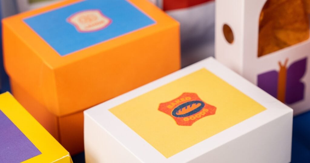 A close-up view of various colourful, custom-branded product boxes, including an orange box with a blue label and a white box.